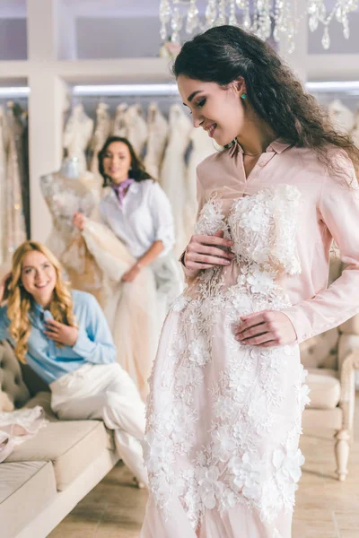 Sposa con abito in pizzo e damigelle d'onore nel salone di nozze — Foto stock