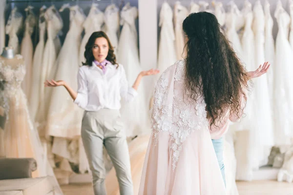 Novia con amigo eligiendo vestido en atelier de boda - foto de stock