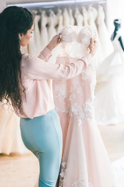 Jeune femme choisir robe de mariée dans le salon de mariage — Photo de stock