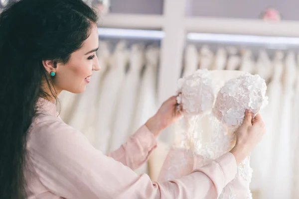 Привлекательная женщина смотрит платье в свадебном магазине моды — стоковое фото