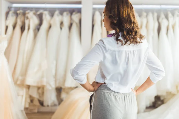 Attraktive Frau betrachtet Kleider im Geschäft für Hochzeitsmode — Stockfoto