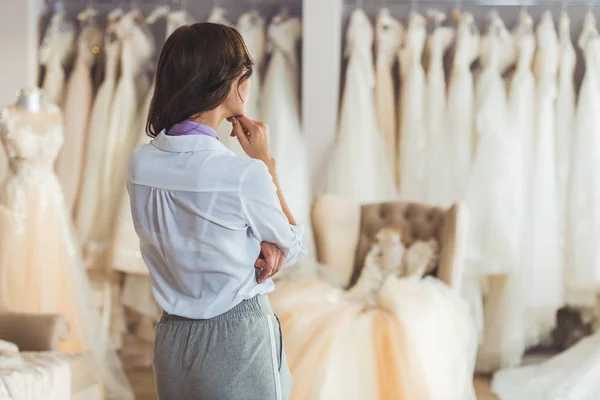 Jovem fêmea escolhendo vestido no salão de casamento — Fotografia de Stock