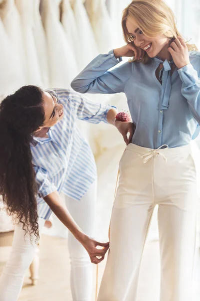 Lächelnde Frau und Näherin messen im Hochzeitssalon — Stockfoto