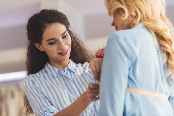 Needlewoman taking measures of blonde woman in wedding salon — Stock Photo