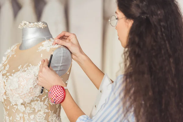 Needlewoman fixing lace dress in wedding fashion shop — Stock Photo