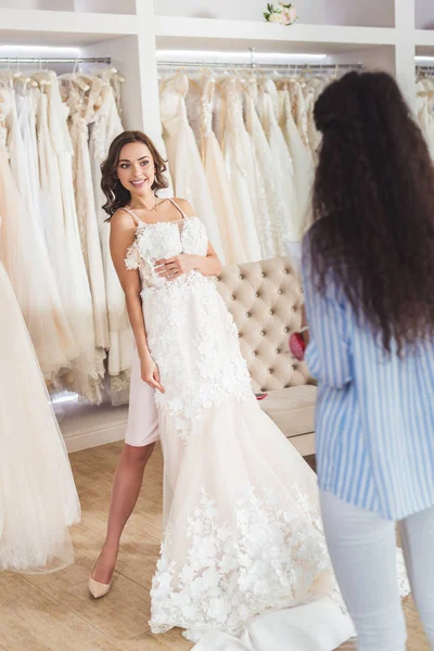 Alfaiate feminino por noiva tentando no vestido de noiva no salão de casamento — Fotografia de Stock