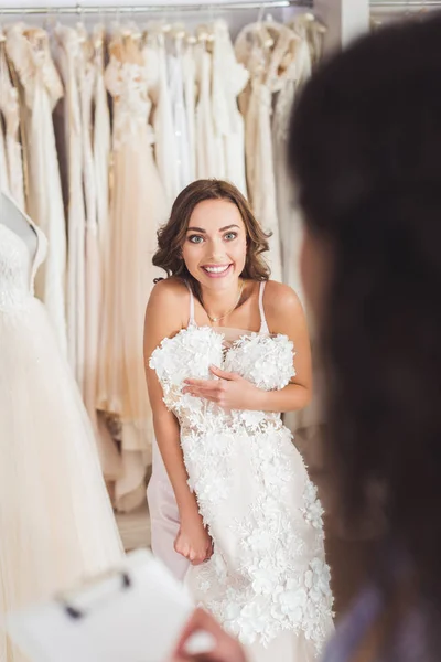 Bella sposa cercando di vestirsi in negozio di moda di nozze — Foto stock