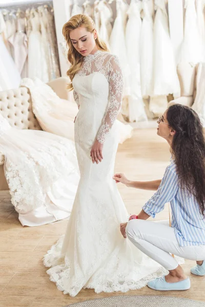 Женский портной, работающий привлекательной невестой в свадебном ателье — стоковое фото