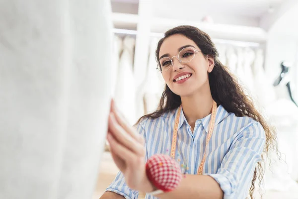 Nadelstickerin befestigt weißes Kleid im Geschäft für Hochzeitsmode — Stockfoto