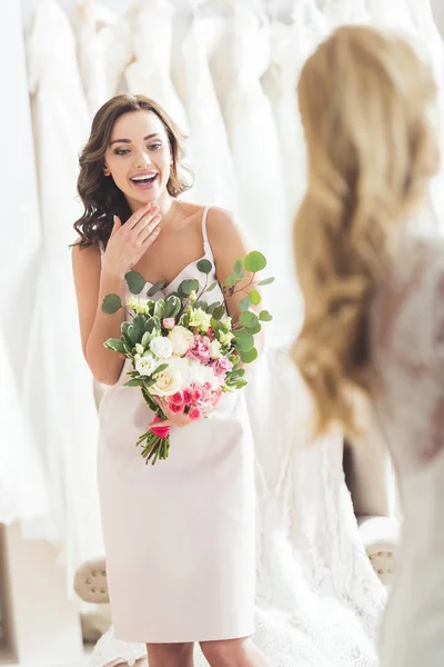 Hübsche Brautjungfer schaut Braut im Hochzeitssalon an — Stockfoto