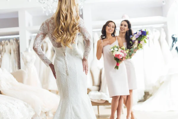 Noiva jovem e damas de honra com buquês na loja de moda do casamento — Fotografia de Stock