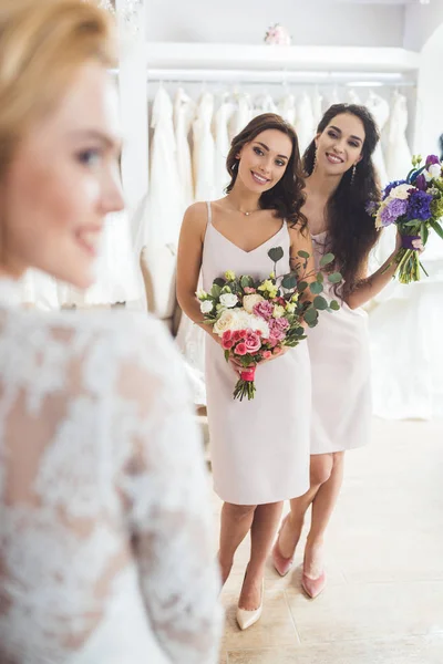 Noiva feliz e damas de honra com flores no salão de casamento — Fotografia de Stock