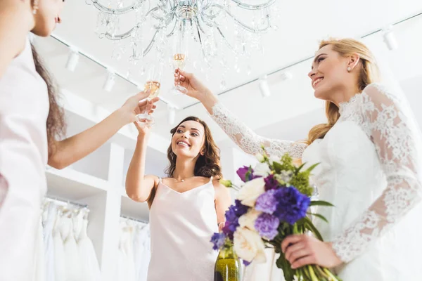 Smiling women in wedding dresses toasting with champagne in wedding salon — Stock Photo