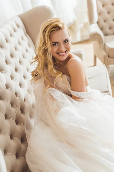 Young bride in tulle dress lying on sofa in wedding fashion shop — Stock Photo