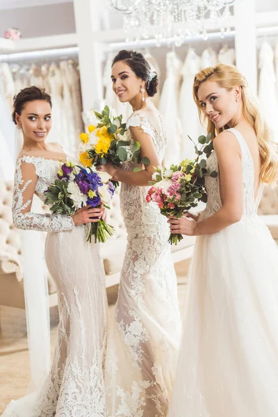 Atractivas novias sosteniendo ramos en el atelier de bodas - foto de stock