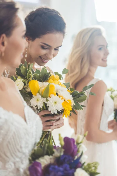 Novias jóvenes sosteniendo tiernos ramos de flores en el salón de bodas - foto de stock