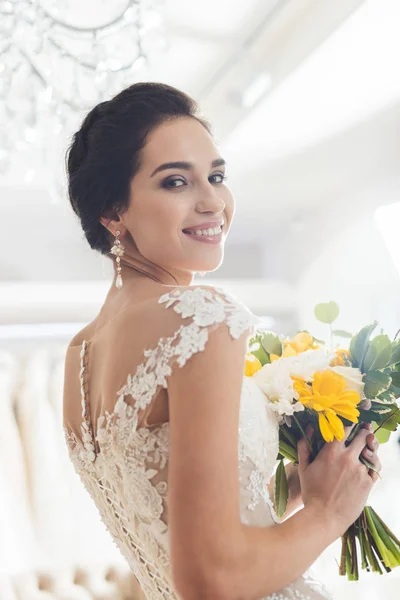 Улыбающаяся невеста с цветами в свадебном салоне — стоковое фото