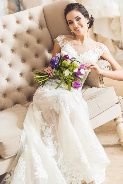 Attraktive Braut mit Blumenstrauß im Geschäft für Hochzeitsmode — Stockfoto