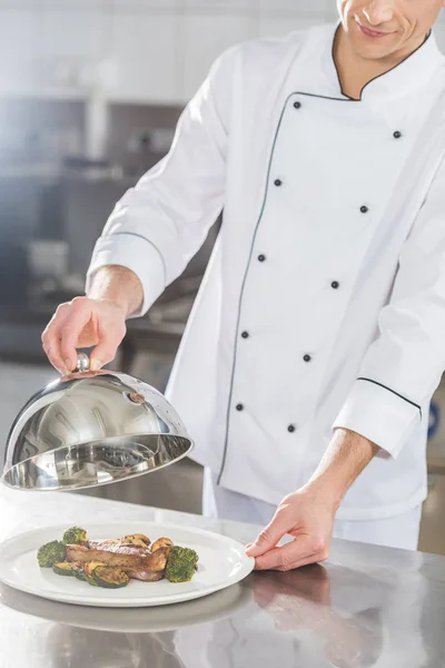 Abgeschnittenes Bild von Koch, der Teller mit Deckel in Restaurantküche deckt — Stockfoto