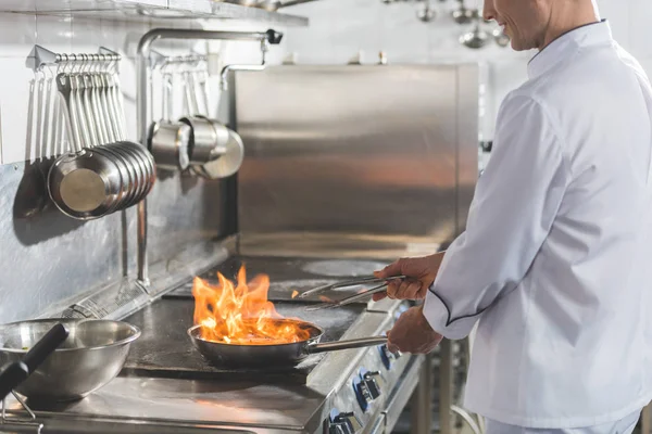 Cropped image of chef frying steak with fire at restaurant kitchen — Stock Photo