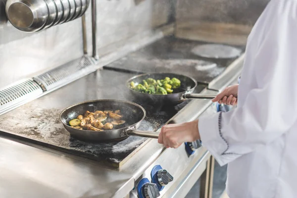 Обрезанный образ повара, жарящего овощи на кухне ресторана — стоковое фото
