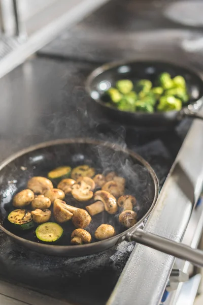 Vegetables on frying pans on stove at restaurant kitchen — Stock Photo