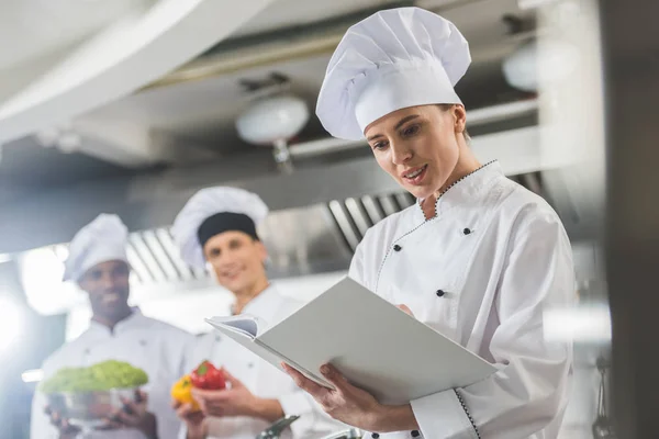 Attractive chef reading recipe at restaurant kitchen — Stock Photo