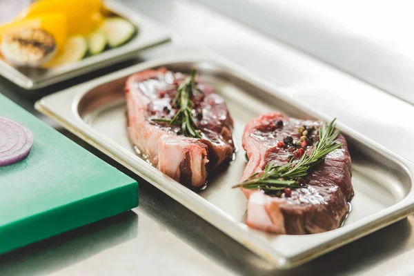 Rohes Fleisch mit Kräutern und Öl auf Tablett auf dem Tisch — Stockfoto
