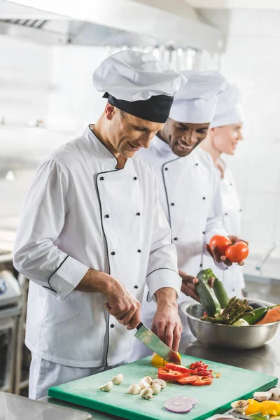 Chef multiculturali sorridenti che preparano il cibo alla cucina del ristorante — Foto stock