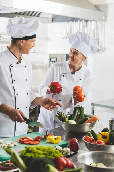 Smiling chefs cooking and looking at each other at restaurant kitchen — Stock Photo