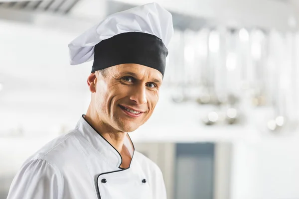Retrato del guapo chef sonriente mirando la cámara en la cocina del restaurante - foto de stock