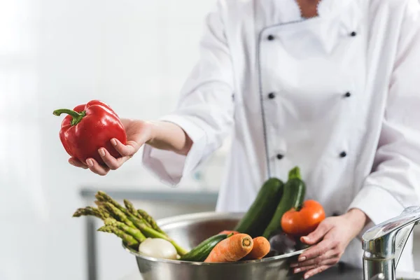 Imagem cortada de chef dando pimentão vermelho para alguém na cozinha do restaurante — Fotografia de Stock