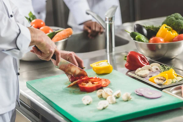 Обрезанный образ шеф-повара, режущего овощи на кухне ресторана — стоковое фото