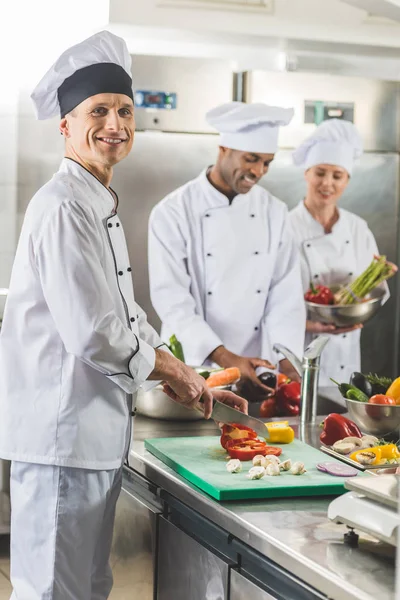 Multicultural chefs cutting and washing vegetables at restaurant kitchen — Stock Photo