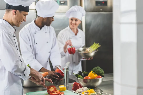 Улыбающиеся мультикультурные повара готовят еду на кухне ресторана — Stock Photo