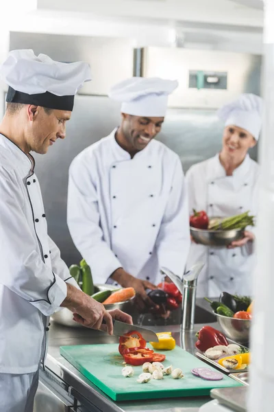 Heureux chefs multiculturels préparer des légumes au restaurant cuisine — Photo de stock