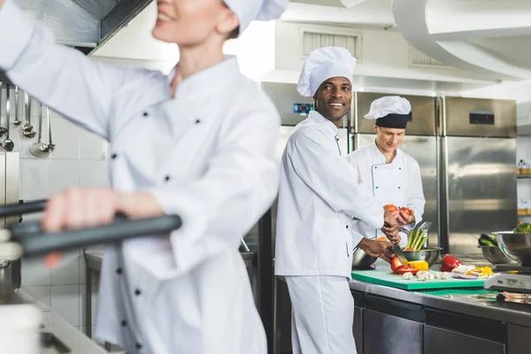 Smiling multicultural chefs cooking at restaurant kitchen — Stock Photo