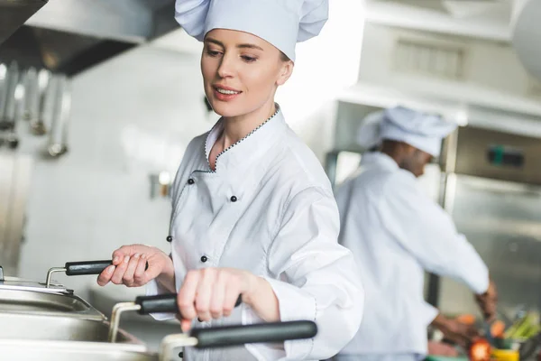 Attractive chef frying food in oil at restaurant kitchen — Stock Photo