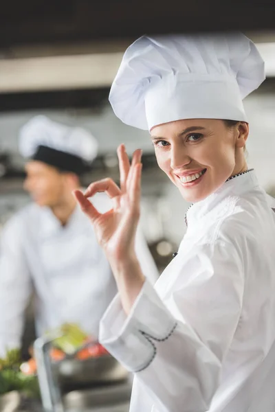 Улыбающийся шеф-повар показывает хороший жест на кухне ресторана — стоковое фото