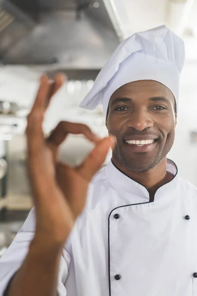 Sonriente afroamericano chef mostrando gesto bien en la cocina del restaurante - foto de stock