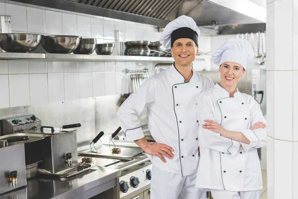 Sorridente masculino e feminino chefs olhando para câmera na cozinha do restaurante — Fotografia de Stock