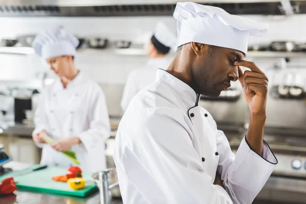 Tired african american chef touching nose bridge at restaurant kitchen — Stock Photo