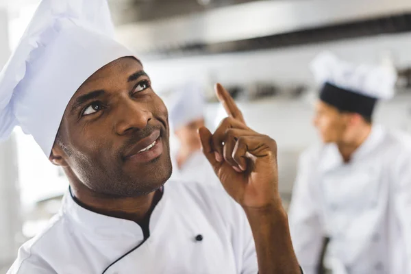 Beau chef afro-américain pointant vers le haut à la cuisine du restaurant — Photo de stock