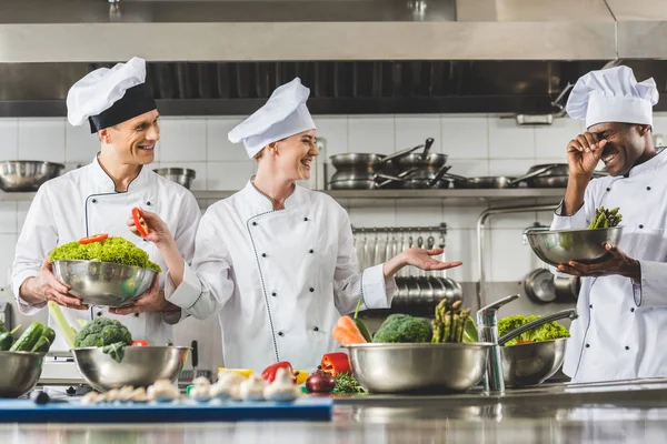 Chefs multiculturales riendo en la cocina del restaurante - foto de stock