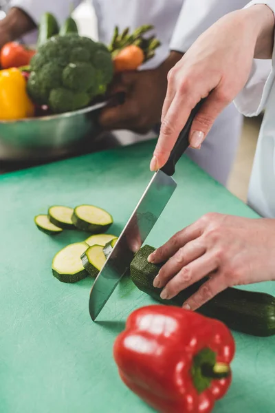 Cropped image of chef cutting zucchini at restaurant kitchen — Stock Photo