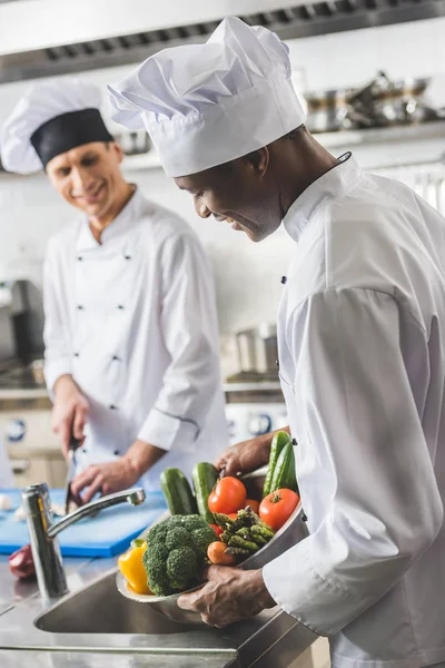 Chef afroamericano che lava verdure nella cucina del ristorante — Foto stock