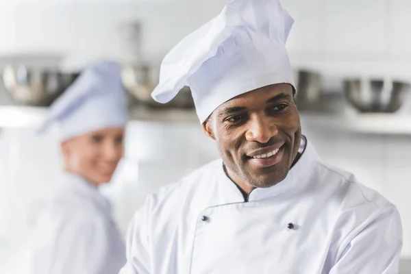 Chefs multiculturales sonrientes en la cocina del restaurante - foto de stock