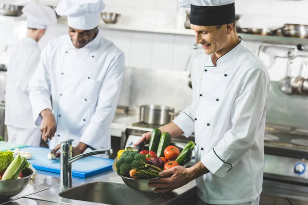Chefs multiculturales felices trabajando en la cocina del restaurante - foto de stock