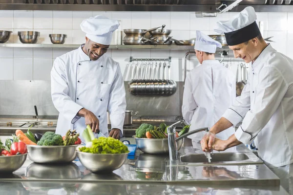 Chefs multiculturales cocinando en la cocina del restaurante - foto de stock