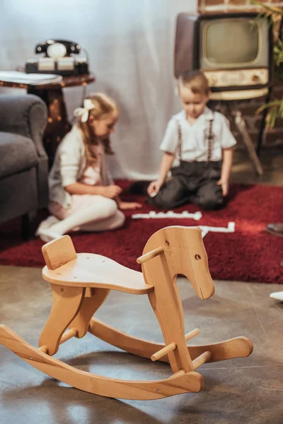 Дерев'яний коник-качалка і маленькі діти грають з плитками доміно вдома, стиль 50-х — стокове фото